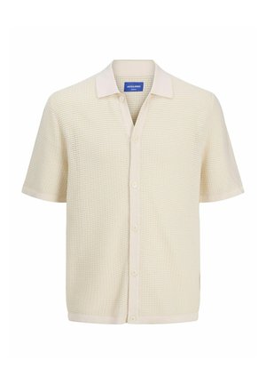 Polo à manches courtes de couleur crème en tissu tricoté texturé, avec une fermeture à boutons et un col contrastant.