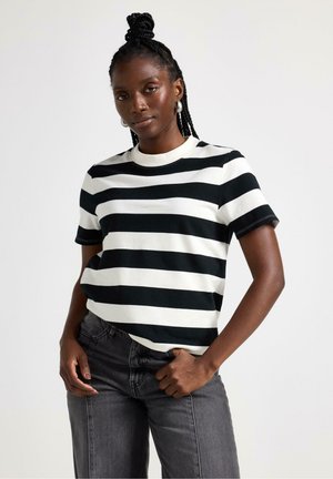 T-shirt a righe bianche e nere con maniche corte e scollatura rotonda, realizzata in tessuto morbido; indossata con jeans grigio scuro.