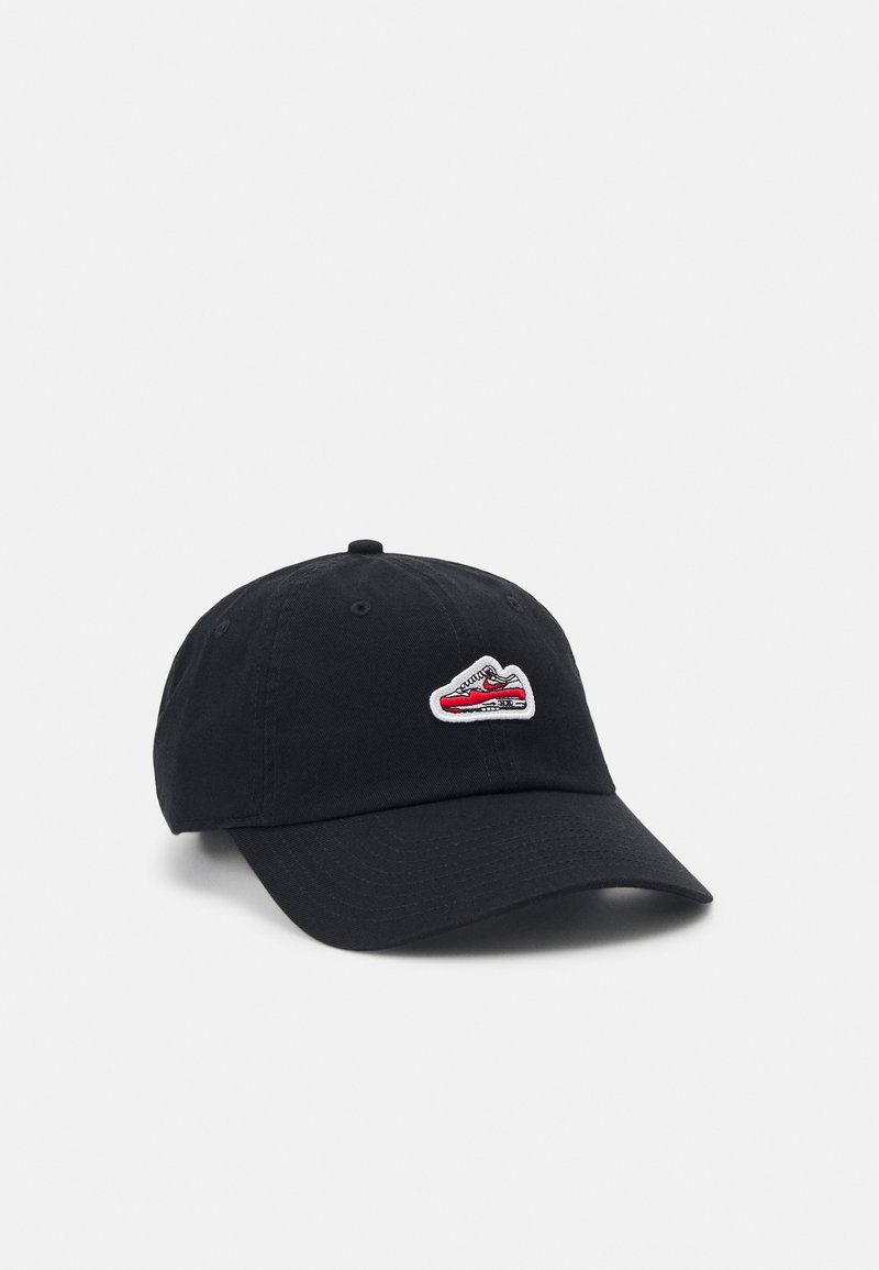 Gorra de algodón negra con visera curva, que presenta un gráfico bordado de zapatilla en blanco y rojo en la parte frontal.