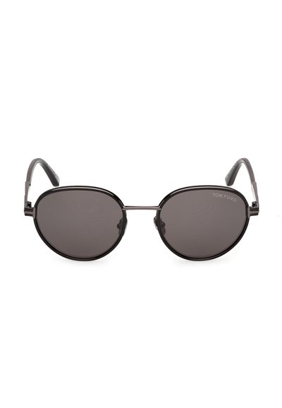Lunettes de soleil rondes noires Tom Ford avec une fine monture métallique et des verres teintés foncés, vues de face sur fond blanc.