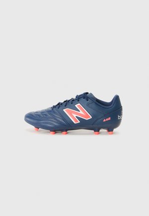 Blue soccer cleat with textured synthetic upper, pink accents, central lacing, and molded studs for traction. Features "N" logo on side.