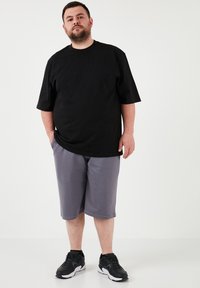 Crna majica kratkih rukava, slobodnog kroja; siva kratka hlače do koljena s elastičnom waist band; crne atletske tenisice. Jednostavan dizajn, ležeran stil.
