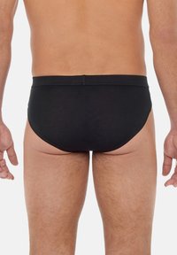 Schwarze Herrenslips aus glattem Stoff, mit schlichtem Design, elastischem Bund und enganliegender Passform. Die Rückansicht zeigt die konturierte Form.