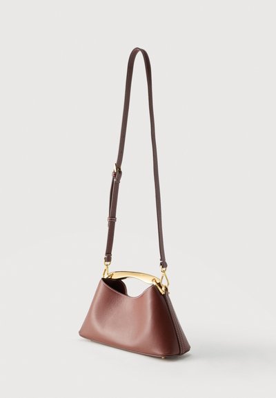 Καφέ δερμάτινη τσάντα ώμου με μακρύ ρυθμιζόμενο λουράκι και χρυσούς μεταλλικούς τόνους στη λαβή, σε ανοιχτό φόντο.