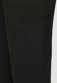 Pantalons cargo noirs avec une poche côté. Fabriqués en tissu durable avec une texture lisse et un design à jambes droites.