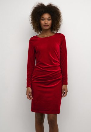 Abito lungo in velluto rosso con scollatura a barca e dettagli arricciati in vita, silhouette aderente e orlo all'altezza del ginocchio.