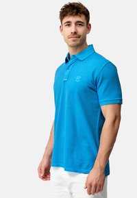 Polo skjorte i lys blå bomull, kortermet, tre-knapp placket, med en liten logo trykket på brystet. Glatt tekstur, uformell design.