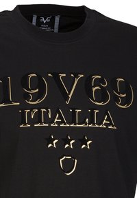 Zwarte katoenen T-shirt met verhoogde gouden letters "19V69 ITALIA" en drie sterren boven een schildembleem. Ronde halslijn, korte mouwen.