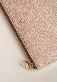 Reißverschlussbeutel aus strukturiertem rosa Stoff mit zartem Muster, ausgestattet mit einem goldfarbenen Druckknopf und einem Reißverschlussanhänger.