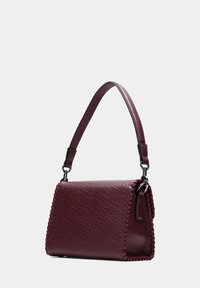 Burgundy läderhandväska med en strukturerad form, som har dekorativ sömnad längs kanterna och en avtagbar, justerbar rem.