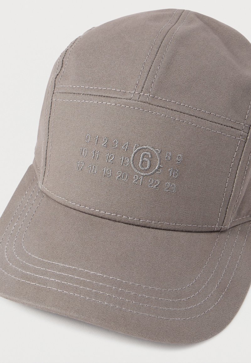 Graue Stoffkappe mit strukturiertem Design. Verfügt über bestickte Zahlen auf der Vorderseite und kontrastierende Ziernähte.