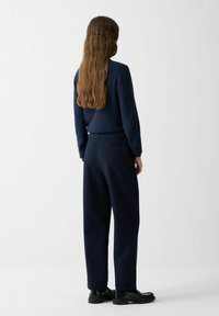 Námornícky sveter s textúrovaným povrchom skombinovaný s námorníckymi nohavicami širokého strihu. Oblečenie má priliehajúci pás a hladký materiál pre pohodlie.