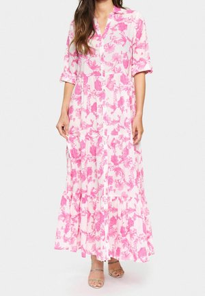 Długa, różowa sukienka w kwiaty z przodem na guziki, z półrękawami i falbaną na dole. Materiał wydaje się lekki; wzór kwiatowy jest wyraźny.