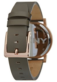 Green leather watch strap with a smooth texture, rose gold buckle, and a round case featuring a clear glass back displaying the brand name.