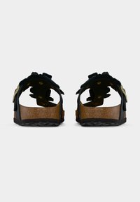 Μαύρα σανδάλια με σόλα από φελλό, διακοσμημένα με ανθισμένες λεπτομέρειες και στρογγυλεμένες περικοπές. Το σχέδιο περιλαμβάνει δύο ρυθμιζόμενους ιμάντες με χρυσά μεταλλικά στοιχεία.