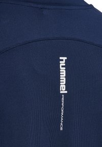 Marineblaues Sportshirt aus glattem Material, mit einem vertikalen weißen "hummel"-Logo und dem Text "PERFORMANCE" auf dem Rücken sowie flachen Nähten.