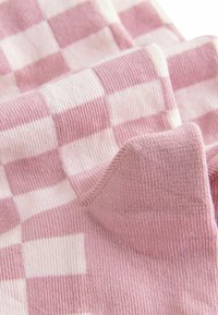 Roosa ja valge ruuduline kangas, millel on sooniline tekstuur, pehme serv ja kerge keerd, esitleb hubast mustrit.