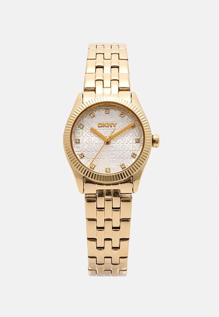Reloj dorado con una esfera plateada decorada con patrón que presenta la marca "DKNY", adornada con pequeños cristales como marcadores de hora. Pulsera de eslabones de metal.
