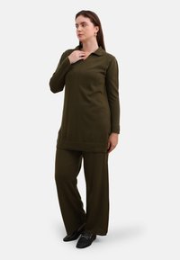 Olijfgroene tuniek met een kraag en lange mouwen, gecombineerd met bijpassende wijde broek. Zachte stoftextuur met minimalistische ontwerpelementen.