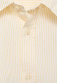 Yellow and white striped button-up shirt, cotton fabric, featuring a classic collar and transparent plastic buttons along the placket.