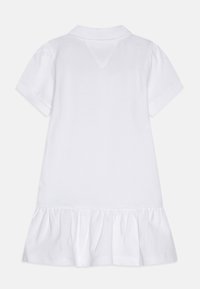 Valkoinen poolomekko, jossa on lyhyet puffihihat, kauluksellinen pääntie ja kerätty röyhelöhelma. Pehmeästä puuvillakankaasta valmistettu, sileä pinta kauttaaltaan.