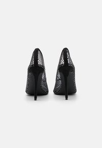 Juodos aukštakulnės bateliai su tinklo viršumi ir zomšos akcentais. Sukurta su smailiu nosiu ir siauru stiletto kulnu. Tekstūruotas dizainas.