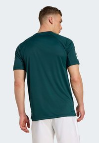 Dark green athletic t-shirt with short sleeves, crewneck design, and smooth texture. Features a logo on the left sleeve and a relaxed fit.