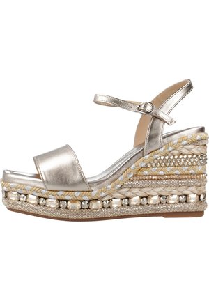 Sandalo wedge dorato metallico con tomaia in pelle liscia, paglia intrecciata e perline decorative sul tacco. Presenta una cinghia con fibbia.
