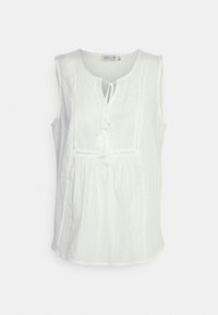 Blouse blanche sans manches en tissu texturé avec un col rond et un détail noué, présentant un panneau délicatement brodé sur le devant.