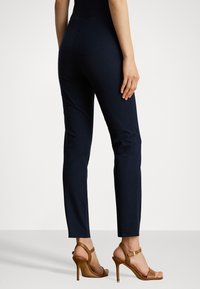 Ναυτικές παντελόνες σε σλιμ φιτ, φτιαγμένες από μαλακό, ελαστικό ύφασμα. Διαθέτουν ψηλή μέση και ομαλή υφή. Συνδυασμένες με ταμπά τακούνια.