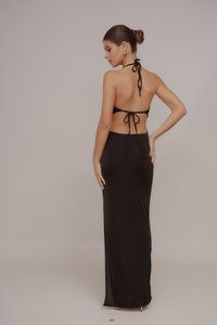 Crna halter haljina s vezanjem na leđima. Uski kroj, do koljena, s glatkom teksturom. Ima otvorena leđa i minimalistički dizajn.