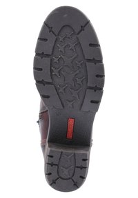 Suela de zapato de cuero marrón con una suela exterior de goma negra texturizada y con un patrón que presenta un diseño de estrellas, con la marca "Pikolinos" en rojo.