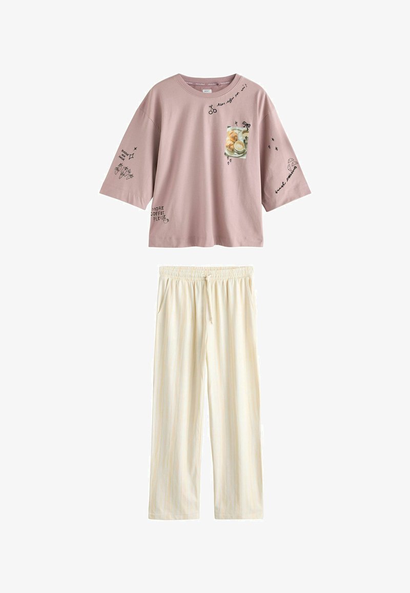 Fioletowo-różowy, oversize'owy T-shirt z motywami kawowymi i tekstem, zestawiony z luźnymi, kremowymi spodniami na sznurek z kieszeniami po bokach.