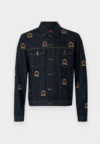 Σκούρο μπλε τζιν μπουφάν με κεντημένα σχέδια με έμβλημα σε κόκκινο και κίτρινο. Διαθέτει δύο τσέπες στο στήθος και αξεσουάρ σε ασημί τόνο. Κλασική γραμμή.