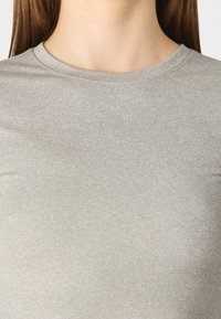 Light grey, short-sleeve tee with a round neckline made of soft, smooth fabric. The texture is even and slightly stretchy.