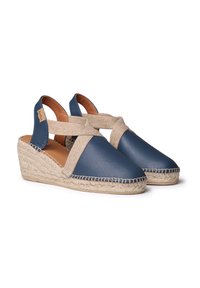 Námořnické kožené espadrilky s křížovými tkaninovými popruhy a tkanými jutovými klíny. Obsahují šité detaily a měkký hnědý interiér.