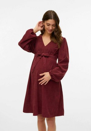 Burgundy corduroy maternity dress with a deep V-neck, long puffed sleeves, and a tied waist, featuring a flared skirt and textured fabric.