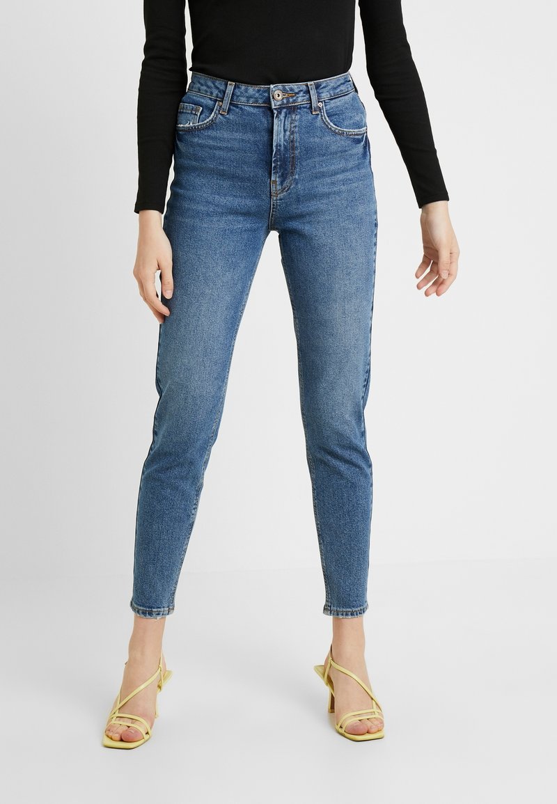 Blå denimhögmidjade jeans med smal passform, med knappstängning, framfickor och subtila slitningar.