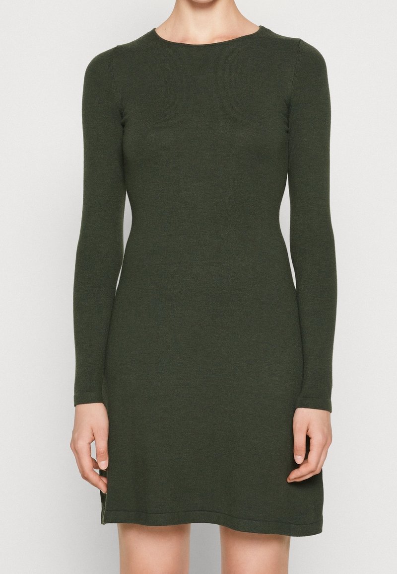 Robe tricotée à manches longues en vert foncé, avec un décolleté rond et une texture côtelée, dotée d'une silhouette légèrement évasée et de fentes latérales.