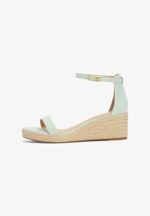 Sandale compensée en daim vert menthe avec une large bride avant, une bride à la cheville avec une boucle en or et une plateforme en jute tressé.