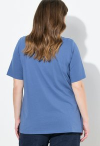 Blå bomullströja med korta ärmar, rund hals och lös passform, har en enkel design utan synliga mönster eller detaljer.