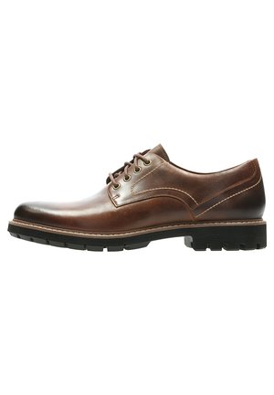 Braune Lederdressschuhe mit einer glatten Oberfläche, runder Zehenpartie, Schnürdesign und einer kontrastierenden schwarzen Gummisohle. Subtile Nahtdetails.