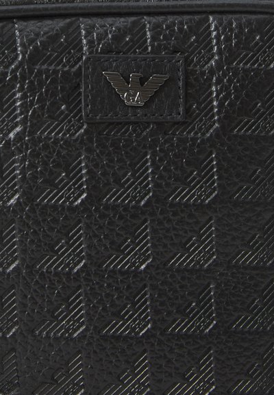 Sort textured lædertaske med et geometrisk mønster og metallogo-detalje. Overfladen har en subtil glans og præget detaljer.