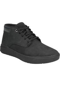 Botines de ante negros con lining de malla, punta redondeada y cordones negros. Cuenta con un logo de marca y una suela de goma texturizada.