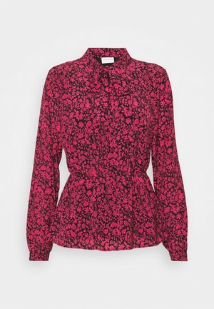 Blouse met lange mouwen met een felroze bloemenpatroon op zwarte stof, voorzien van een hoge hals met een gestrikte strik en een getailleerde taille.