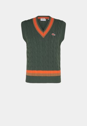 Grüner ärmelloser Strickpullover mit V-Ausschnitt, der einen orange-braun gestreiften Saum und ein kleines Logo auf der Brust hat.