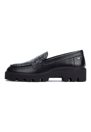 Mocasines de cuero negro con acentos de tachuelas, una suela de plataforma gruesa y una textura suave. Presenta un detalle de lazo decorativo en la parte frontal.