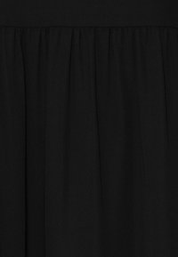 Black fabric with a smooth texture featuring pleats along the lower edge, creating a draped effect. No visible patterns or hardware.