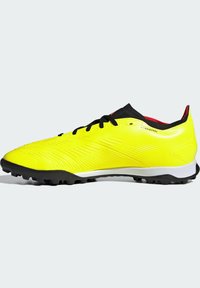 Crampons de football jaunes avec un dessus synthétique texturé, des lacets noirs et des accents rouges. Équipés d'une semelle en caoutchouc noir avec des crampons moulés pour une meilleure traction.