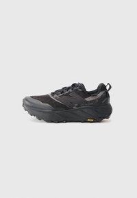 Trail running shoe in black with textured upper and synthetic material. Features a Vibram outsole and reinforced toe cap. Light cushioning visible.